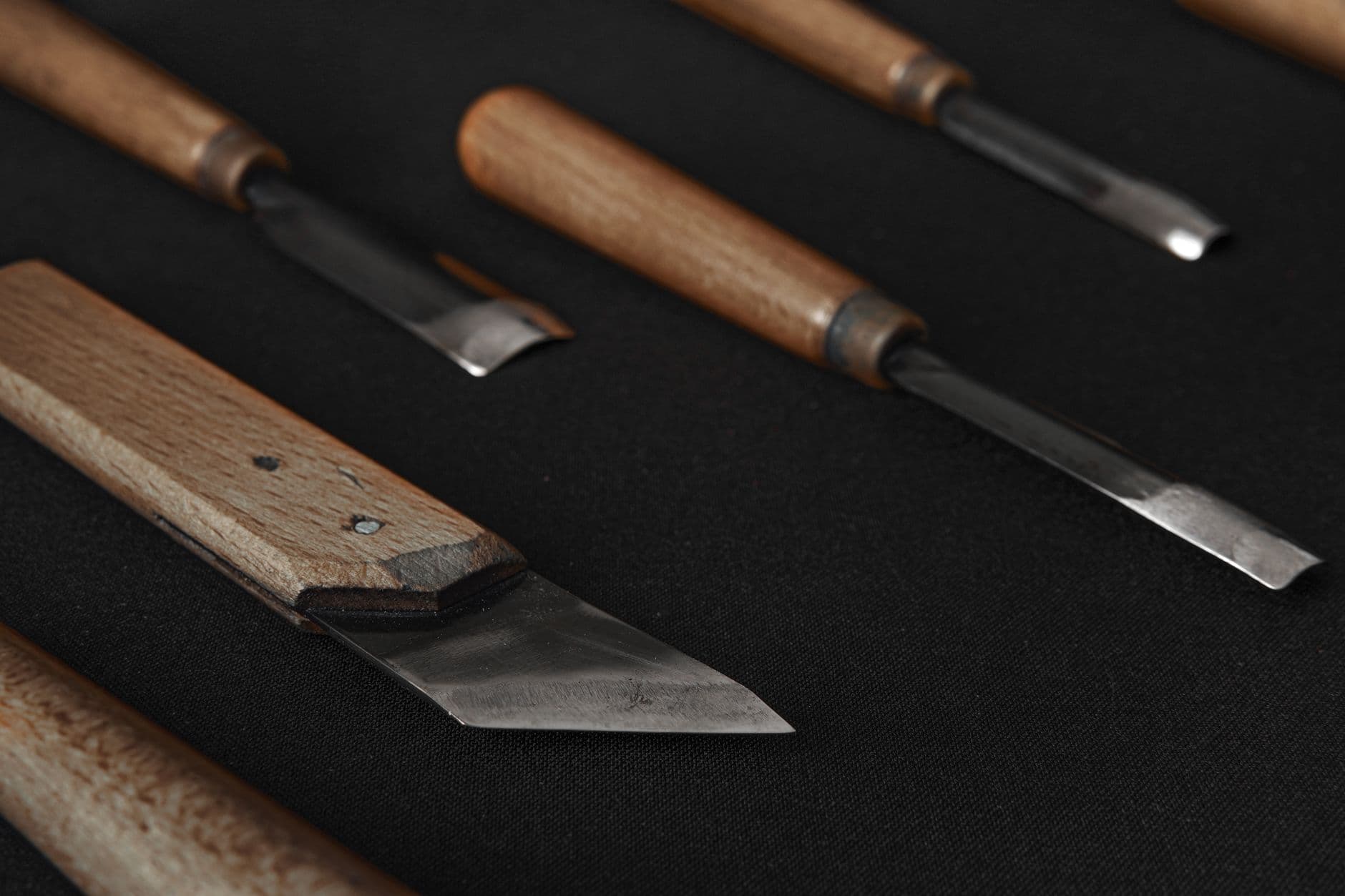 A detailed photo of woodworking tools with sharp blades and wooden handles on a black background.